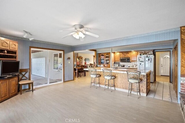 kitchen with a kitchen bar, white fridge, light hardwood / wood-style floors, backsplash, and ceiling fan