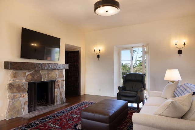 living room with dark wood-type flooring and a stone fireplace