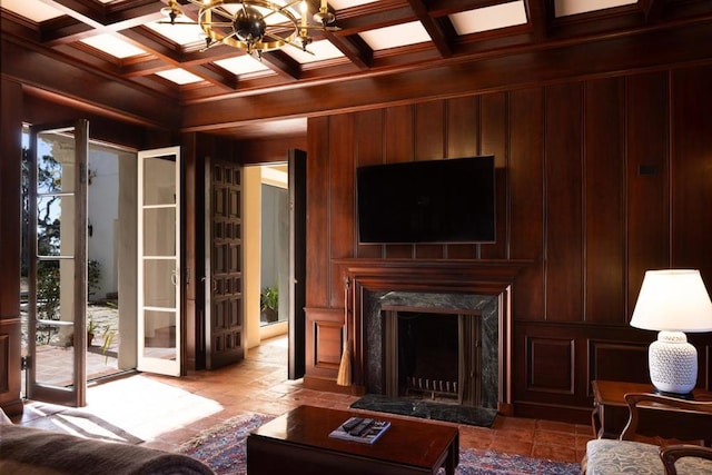 living room with a fireplace, a notable chandelier, wood walls, beam ceiling, and coffered ceiling