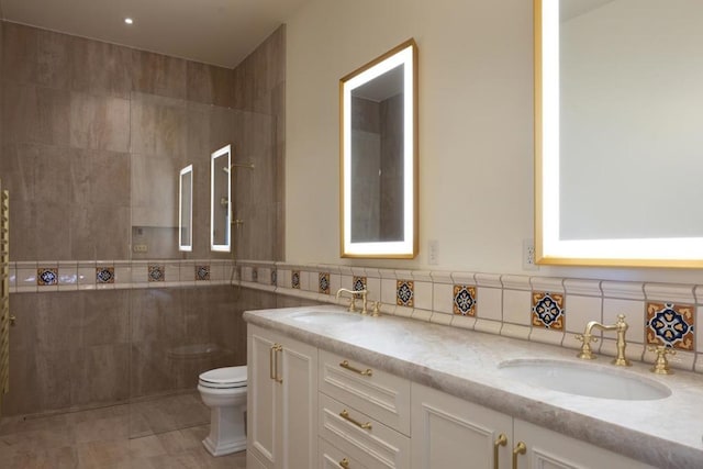 bathroom featuring toilet, vanity, and tile walls