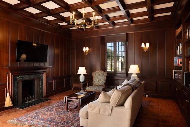 living room with a fireplace, beamed ceiling, wooden walls, an inviting chandelier, and coffered ceiling