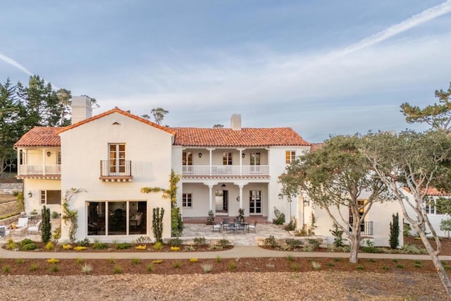 back of property with a patio area, french doors, and a balcony