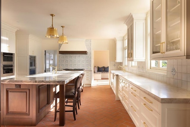 kitchen with decorative light fixtures, a kitchen breakfast bar, backsplash, and white cabinetry