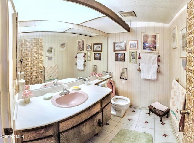 bathroom with tile patterned flooring, vanity, a textured ceiling, and toilet