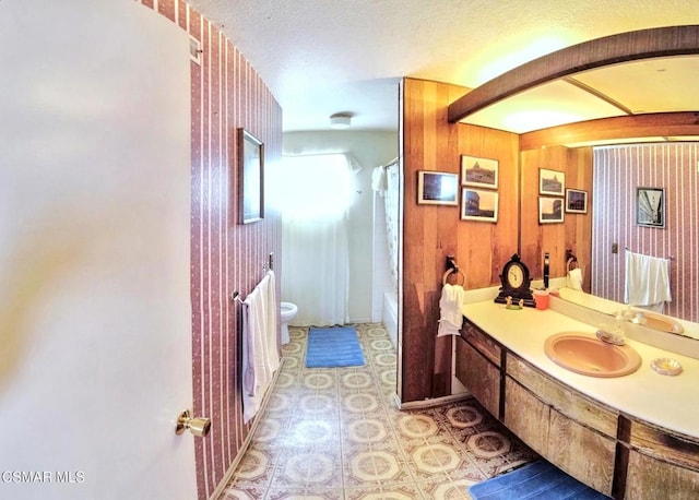 full bathroom with shower / tub combo with curtain, vanity, toilet, and wood walls