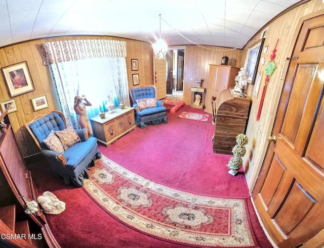 living area with carpet, a chandelier, and wooden walls