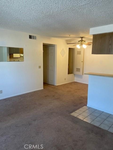 carpeted spare room featuring a textured ceiling and ceiling fan