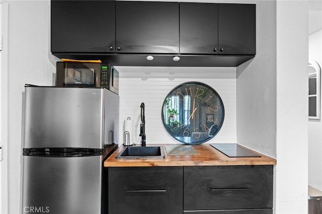 kitchen with sink, wooden counters, and stainless steel refrigerator