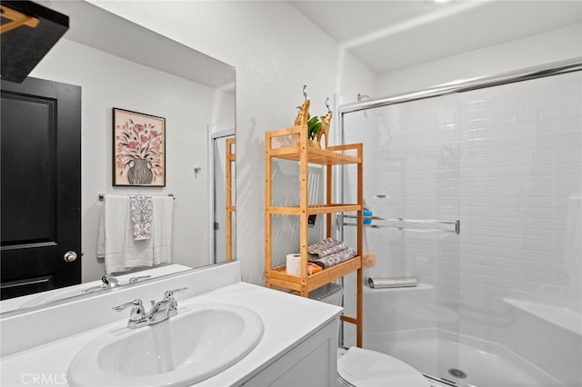 bathroom featuring toilet, a shower with door, and vanity