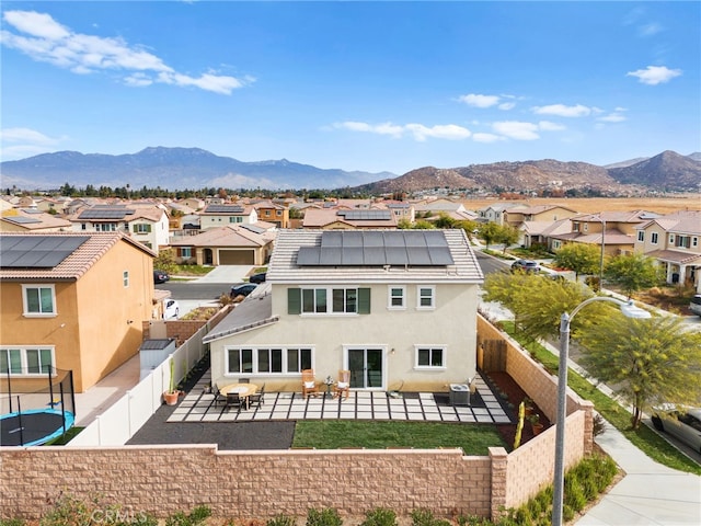 rear view of house featuring a mountain view, solar panels, and a patio