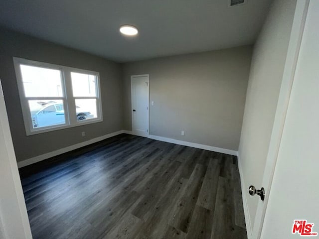 unfurnished room featuring dark wood-type flooring