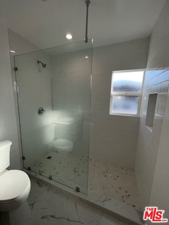 bathroom featuring toilet and tiled shower