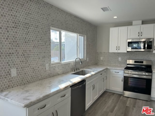 kitchen with sink, light stone counters, appliances with stainless steel finishes, dark hardwood / wood-style floors, and white cabinets