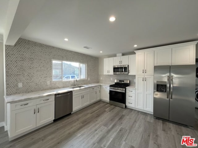 kitchen with white cabinetry, stainless steel appliances, sink, and light wood-type flooring