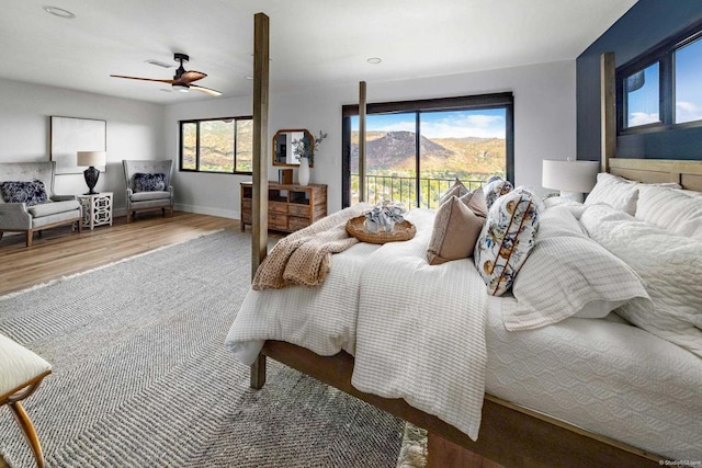 bedroom with hardwood / wood-style flooring, ceiling fan, access to exterior, and a mountain view