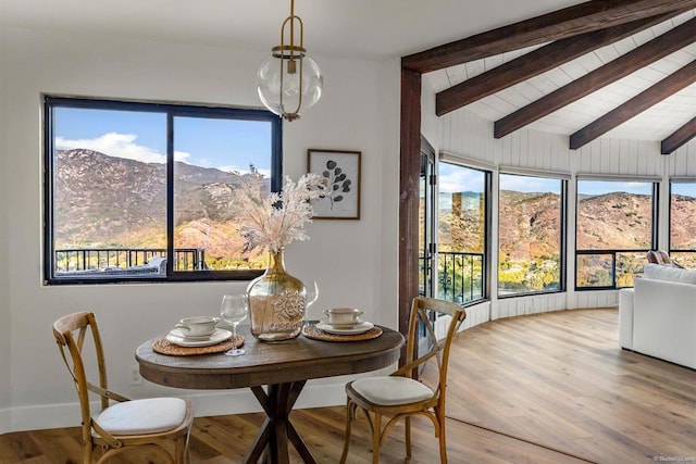 dining room featuring a mountain view, hardwood / wood-style floors, and vaulted ceiling with beams