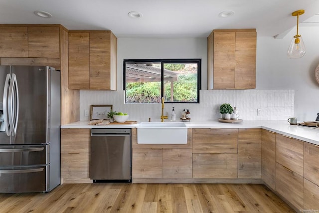 kitchen featuring sink, tasteful backsplash, light hardwood / wood-style flooring, pendant lighting, and appliances with stainless steel finishes