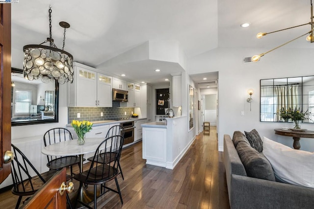 kitchen featuring decorative backsplash, white cabinets, appliances with stainless steel finishes, and vaulted ceiling