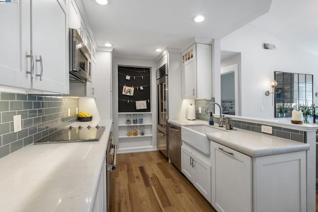 kitchen with dark hardwood / wood-style floors, decorative backsplash, sink, built in appliances, and white cabinets