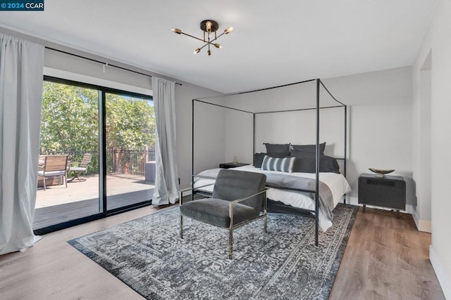 bedroom featuring access to outside, wood-type flooring, and a notable chandelier