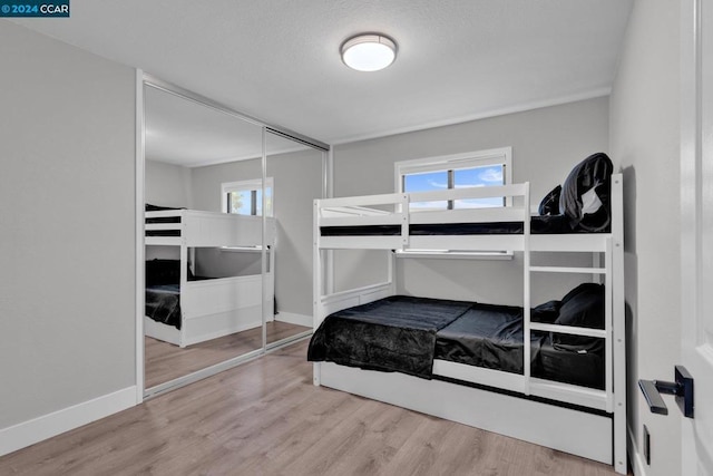 bedroom featuring light wood-type flooring, a closet, and multiple windows