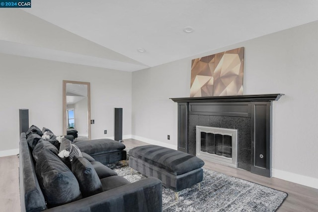 living room with hardwood / wood-style flooring, lofted ceiling, and a tiled fireplace