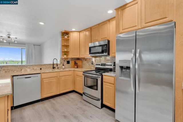 kitchen featuring appliances with stainless steel finishes, backsplash, light wood-type flooring, light brown cabinetry, and sink