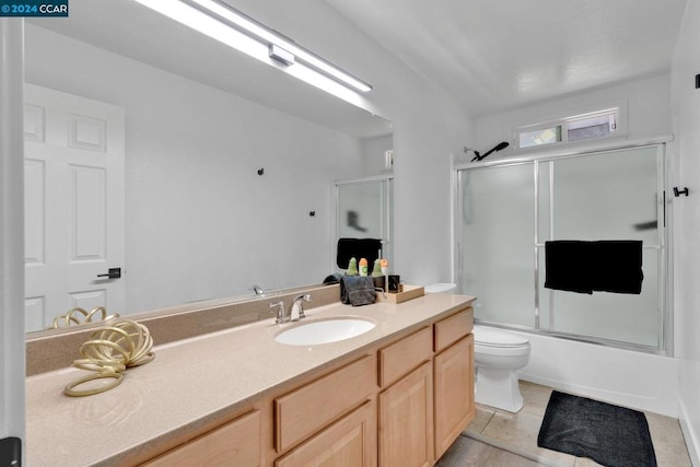 full bathroom with bath / shower combo with glass door, tile patterned floors, vanity, and toilet