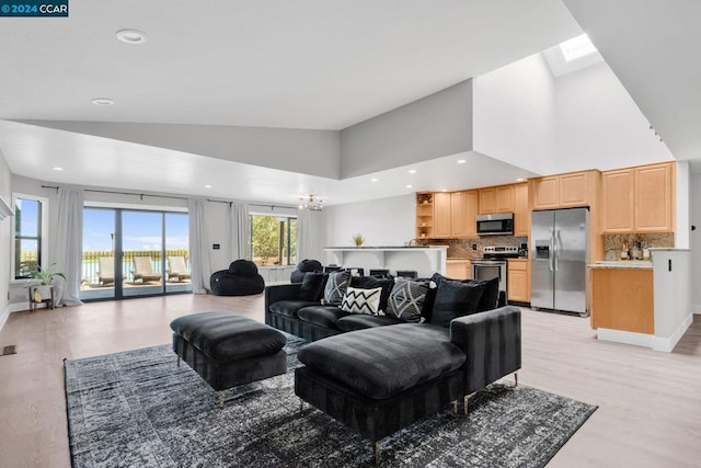 living room featuring light wood-type flooring, a notable chandelier, and high vaulted ceiling