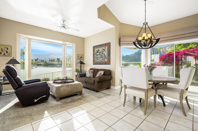 dining area featuring ceiling fan with notable chandelier, a water and mountain view, a wealth of natural light, and light tile patterned floors