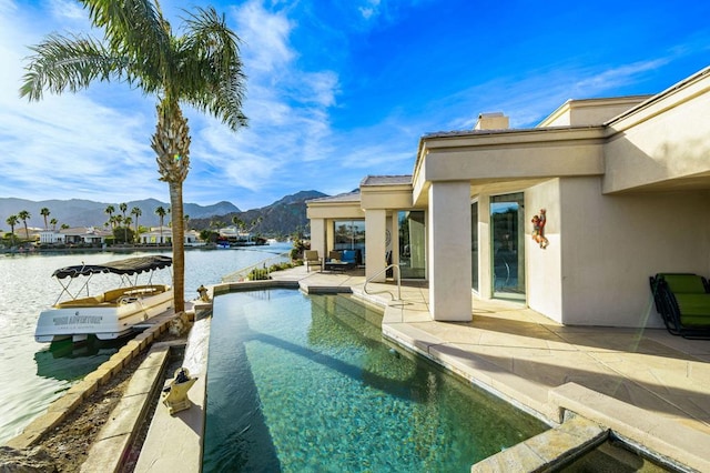 view of swimming pool featuring a boat dock, a patio area, and a water and mountain view