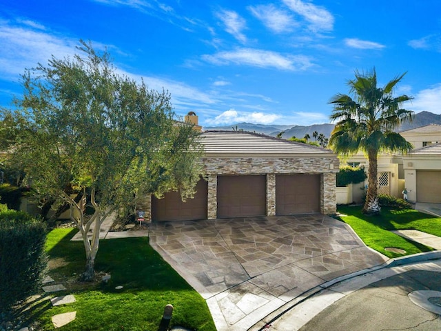 view of front of property featuring a front lawn, a garage, and a mountain view