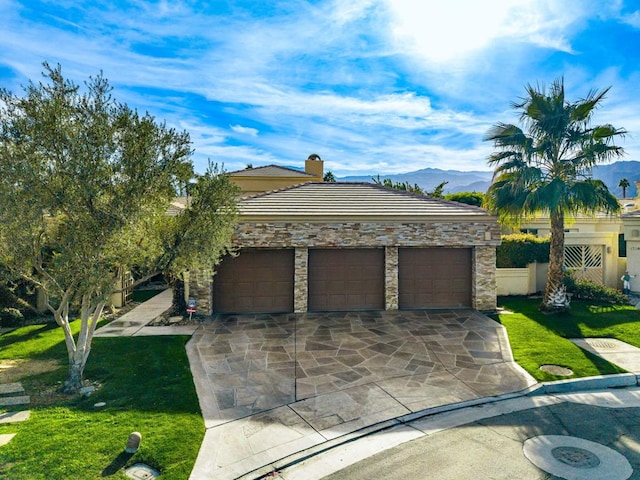 view of front facade featuring a front lawn, a garage, and a mountain view