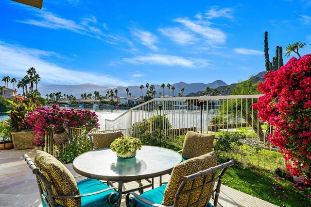 view of patio with a water and mountain view and a balcony