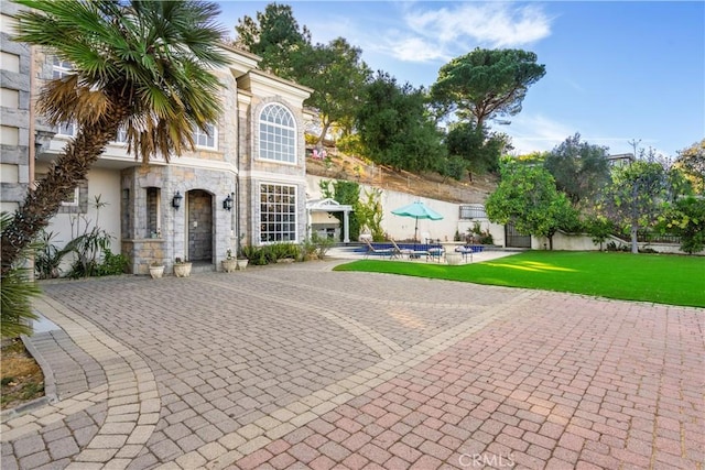 view of front of house featuring a front yard, a swimming pool, and a patio area