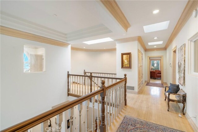 corridor with light hardwood / wood-style floors, a skylight, and ornamental molding