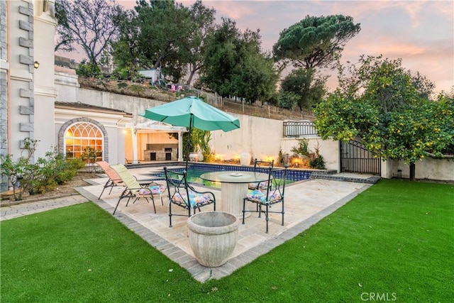 pool at dusk with a patio area and a yard