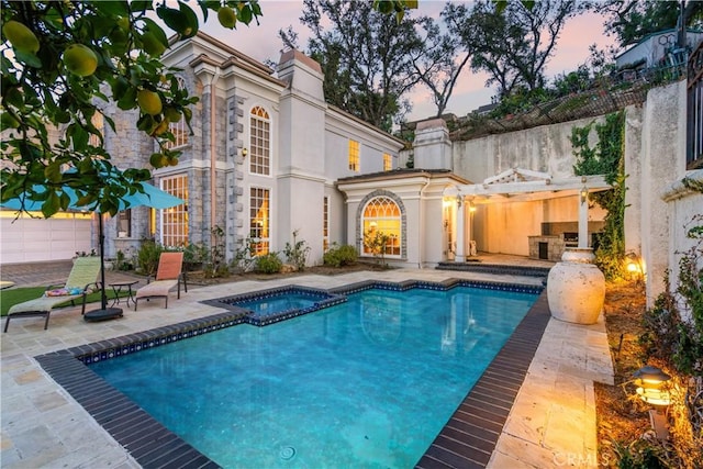 pool at dusk featuring an in ground hot tub and a patio