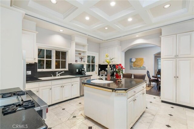 kitchen with coffered ceiling, a kitchen island, backsplash, and white cabinets