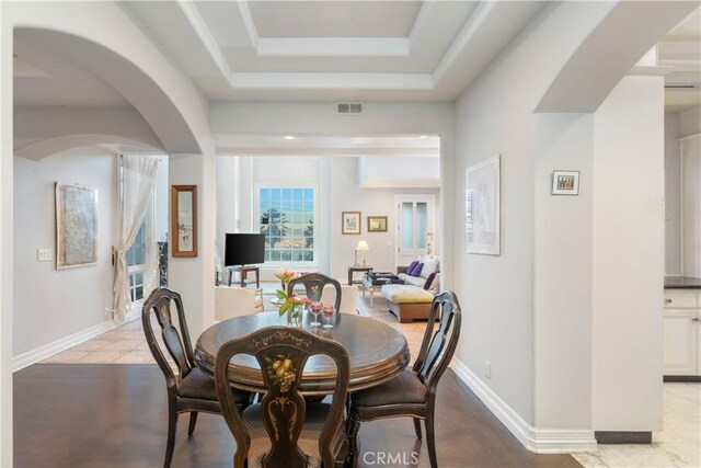 tiled dining space with a tray ceiling