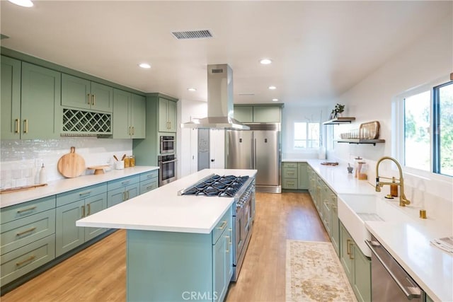 kitchen featuring green cabinets, premium appliances, and island exhaust hood