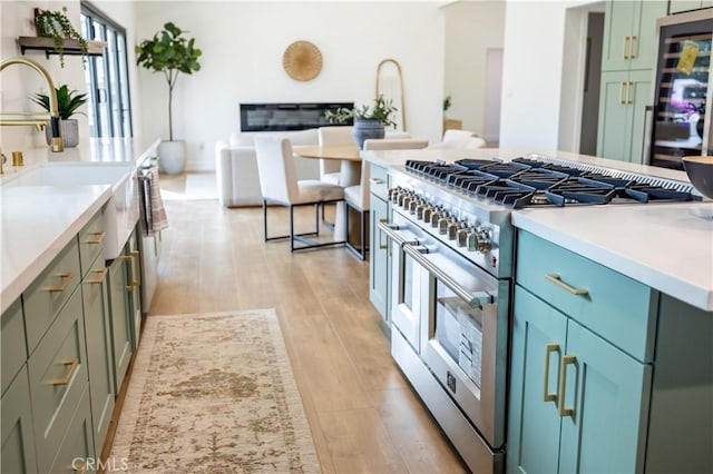 kitchen with range with two ovens, green cabinets, light countertops, and light wood finished floors