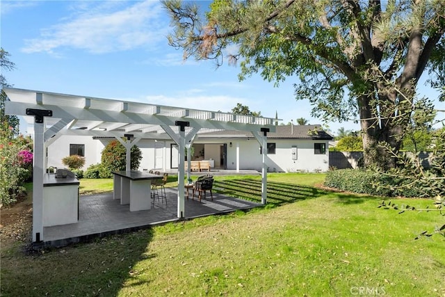 back of house with a lawn, outdoor dry bar, exterior kitchen, a patio area, and a pergola