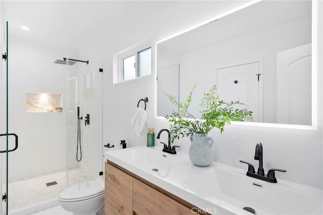 full bath featuring toilet, a stall shower, double vanity, and a sink