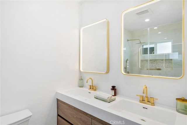 bathroom with a stall shower, a sink, toilet, and double vanity