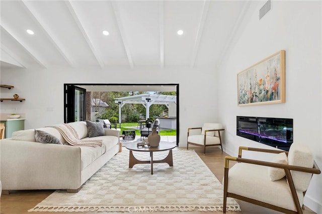 living area featuring wood finished floors, a glass covered fireplace, visible vents, and recessed lighting