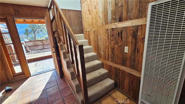 staircase featuring tile patterned flooring and wood walls