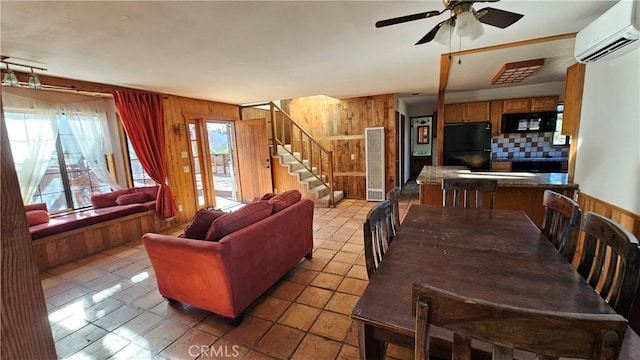 tiled dining area featuring ceiling fan, wood walls, and a wall mounted air conditioner