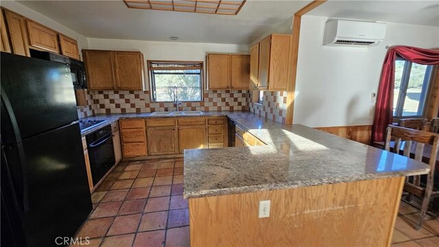 kitchen with tasteful backsplash, black appliances, sink, a wall mounted air conditioner, and stone countertops