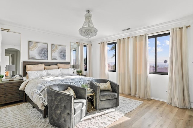 bedroom featuring baseboards, visible vents, arched walkways, ornamental molding, and wood finished floors